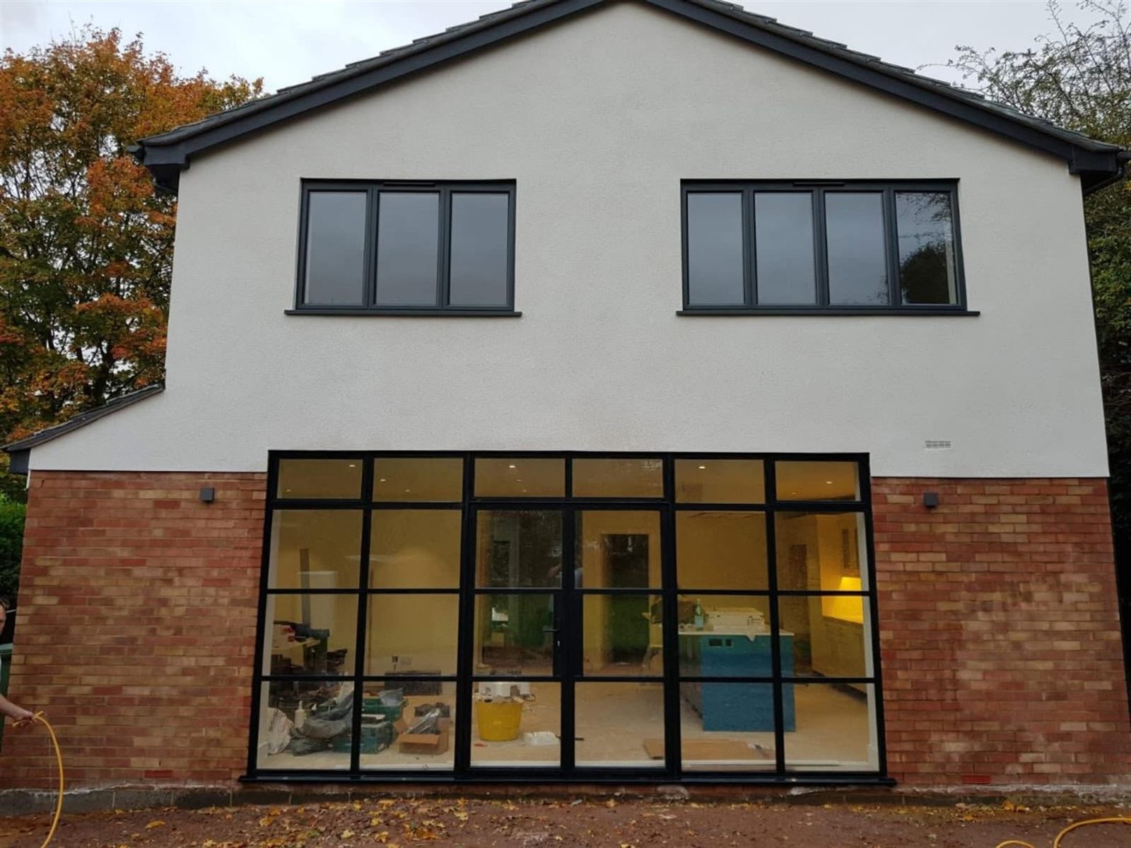 Rear elevation of a new-build house with a full-height black steel-look glazed screen and French doors, and anthracite grey windows above