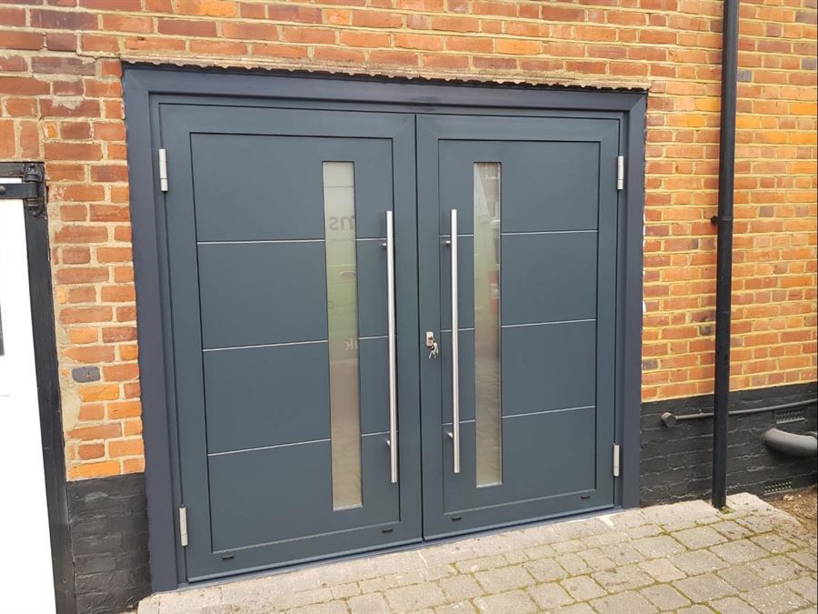 Anthracite grey aluminium double doors with full-height bar handles and slim glazed panels, fitted to a commercial unit