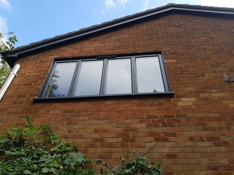 Four-pane anthracite grey aluminium window fitted into the brick gable of a house